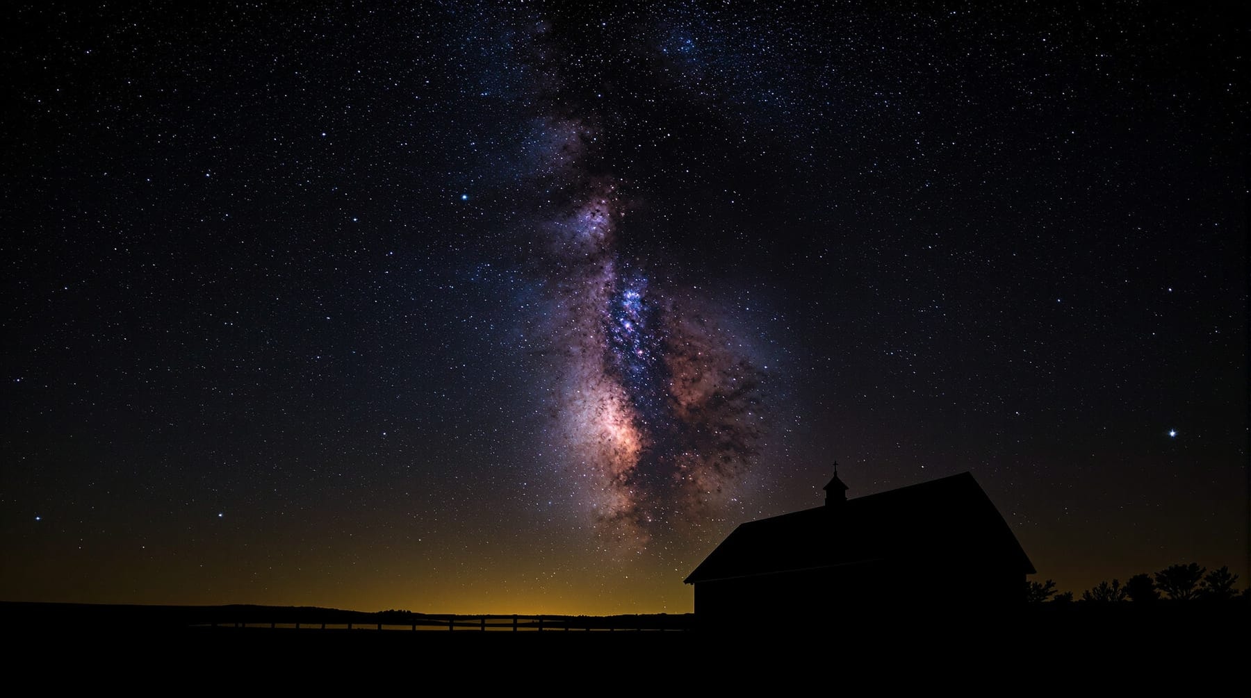 The summer Milky Way rising above a rural horizon with a faint skyglow band below